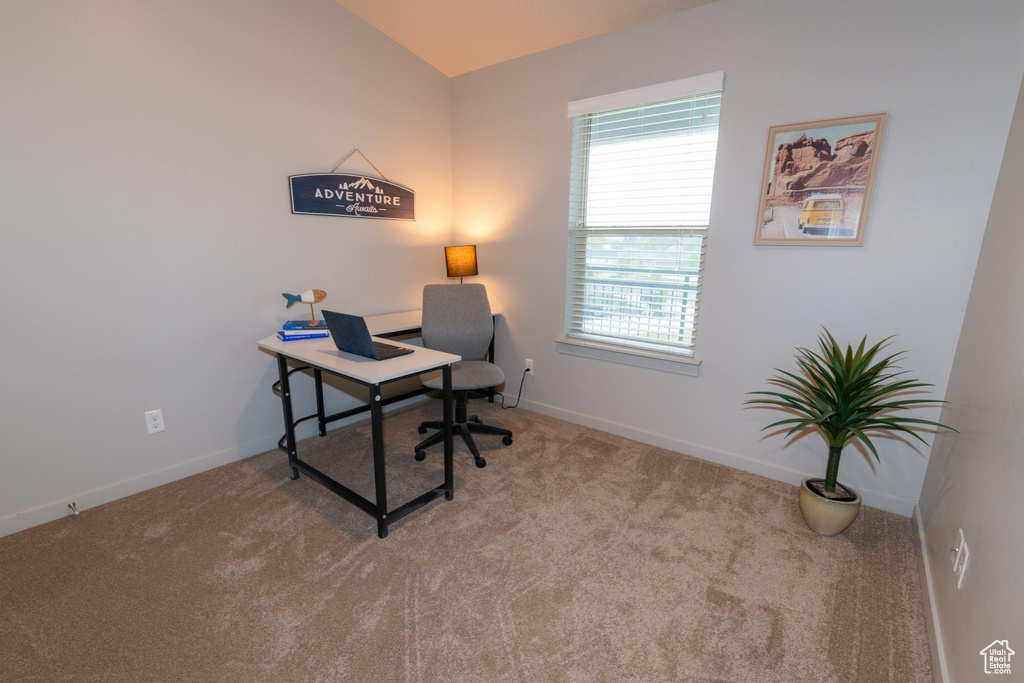 Carpeted home office featuring baseboards and lofted ceiling