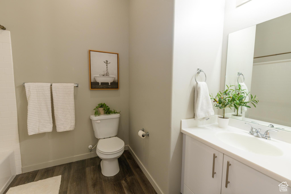 Full bathroom with vanity, baseboards, toilet, and wood finished floors