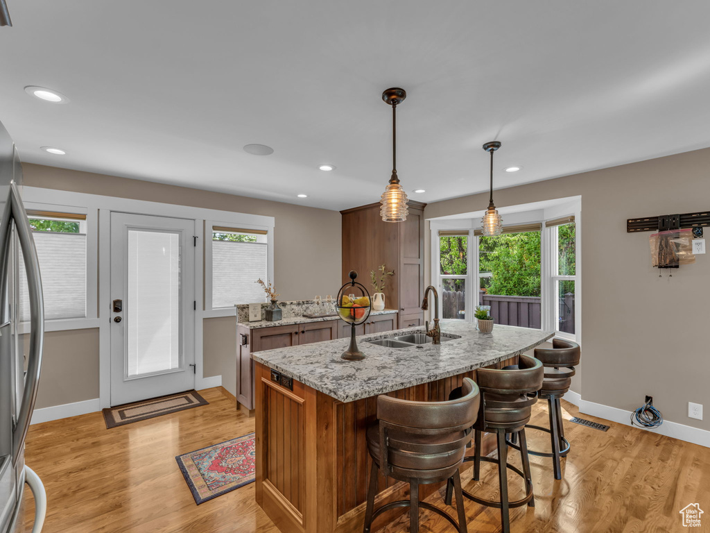 Kitchen with light stone counters, a sink, light wood finished floors, and a healthy amount of sunlight