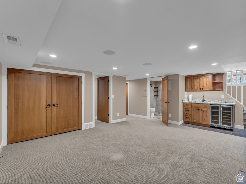 Unfurnished living room featuring wine cooler, baseboards, recessed lighting, and wet bar