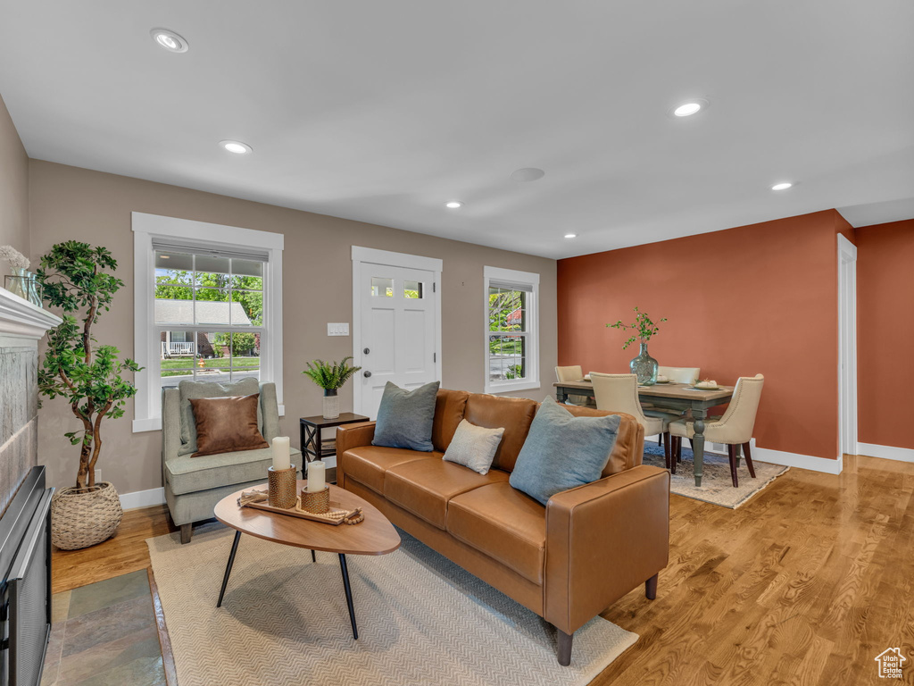 Living area featuring a tiled fireplace, light wood-style floors, recessed lighting, and a wealth of natural light