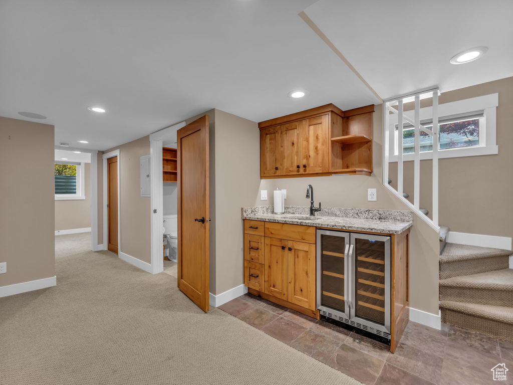 Bar featuring a sink, beverage cooler, baseboards, wet bar, and stairway