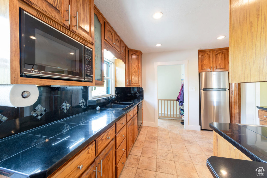 Kitchen featuring decorative backsplash, a sink, baseboards, black appliances, and recessed lighting