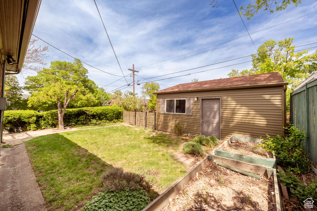 View of yard with fence, an outbuilding, and a vegetable garden
