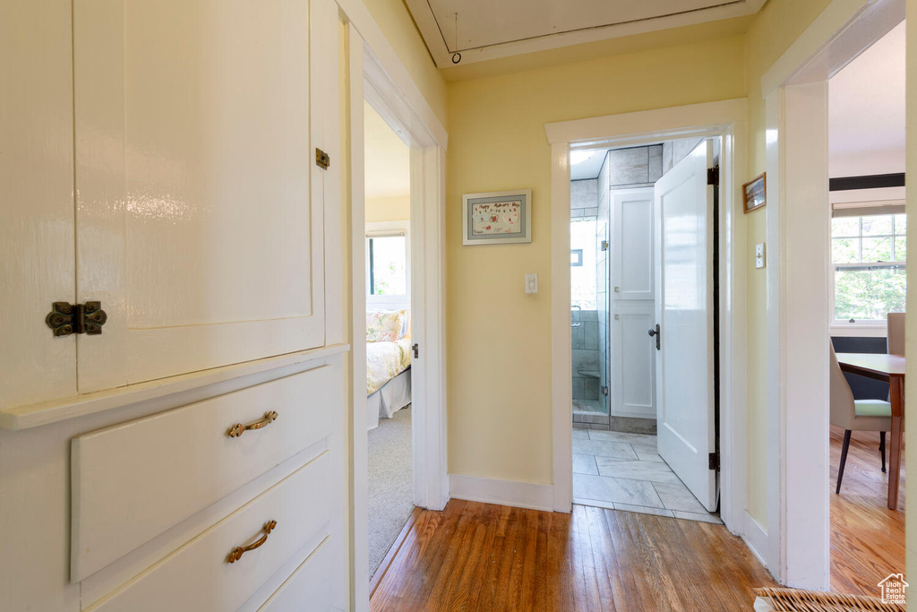 Corridor featuring baseboards, wood finished floors, and attic access