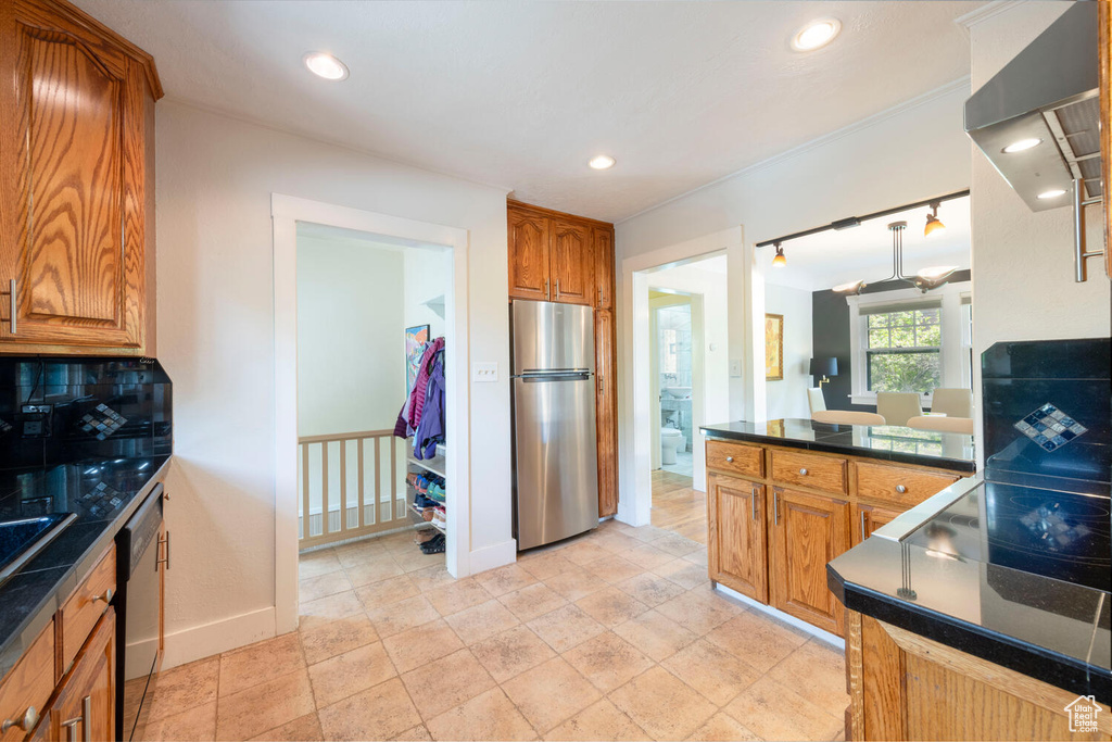 Kitchen featuring dark countertops, appliances with stainless steel finishes, tasteful backsplash, brown cabinets, and recessed lighting