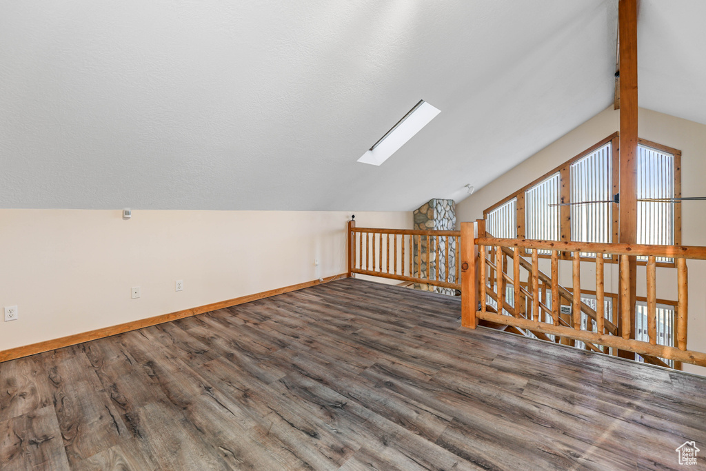 Bonus room with baseboards, lofted ceiling with skylight, and wood finished floors