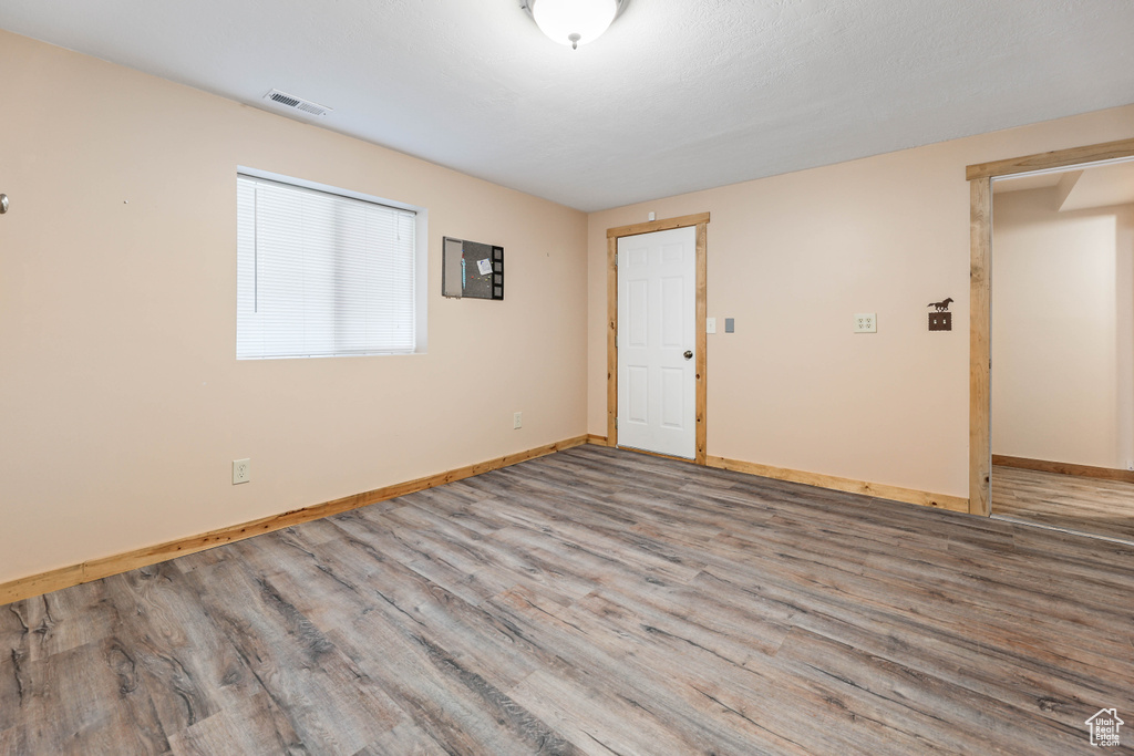 Unfurnished room featuring baseboards, wood finished floors, and visible vents