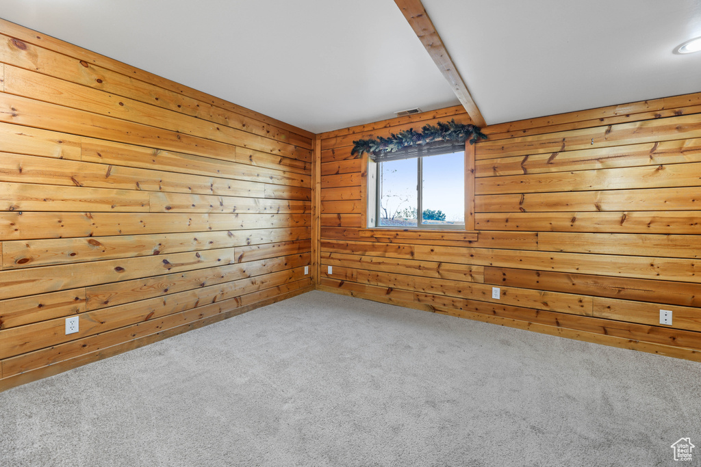 Empty room featuring wooden walls and carpet