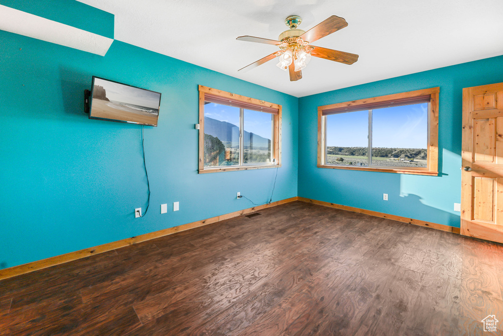Empty room with baseboards, ceiling fan, wood finished floors, and visible vents