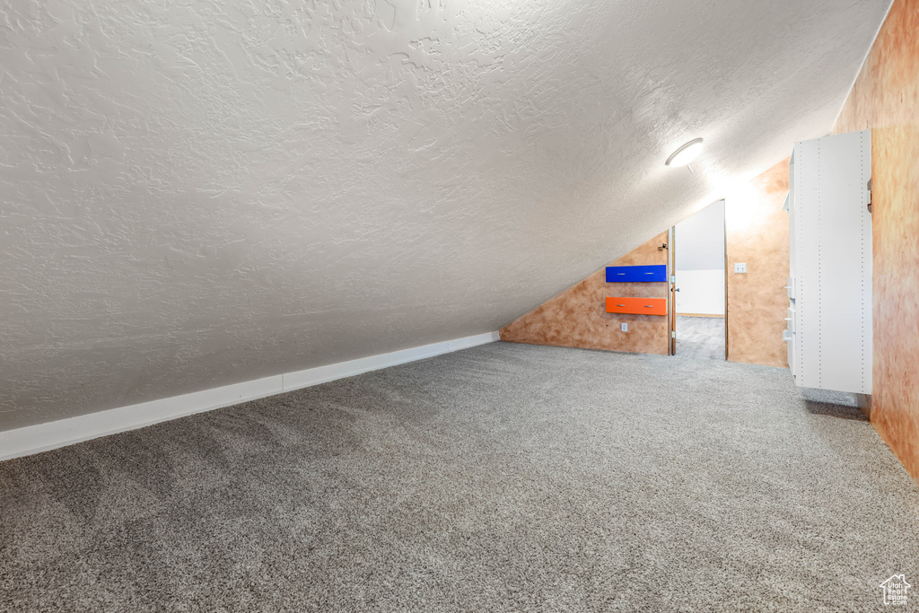 Bonus room with carpet floors, a textured ceiling, and lofted ceiling