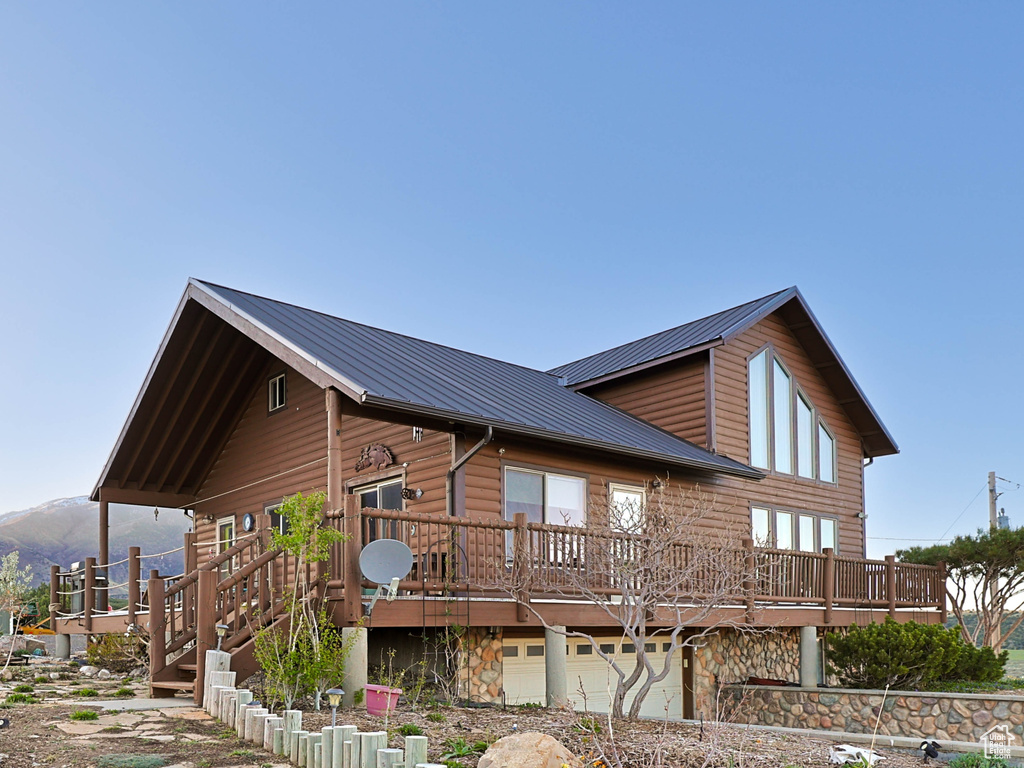 View of side of home with a garage, stone siding, a deck, and metal roof
