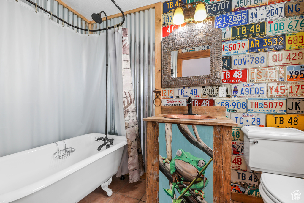 Bathroom with a sink, tile patterned flooring, a soaking tub, and toilet