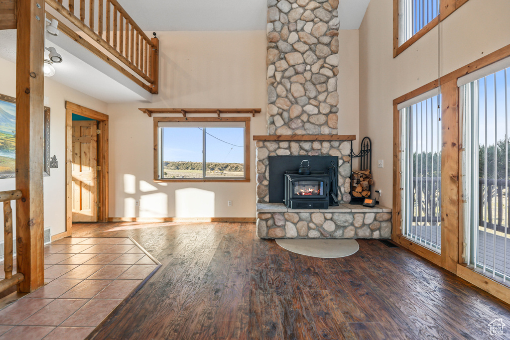 Unfurnished living room featuring baseboards, a towering ceiling, and wood finished floors