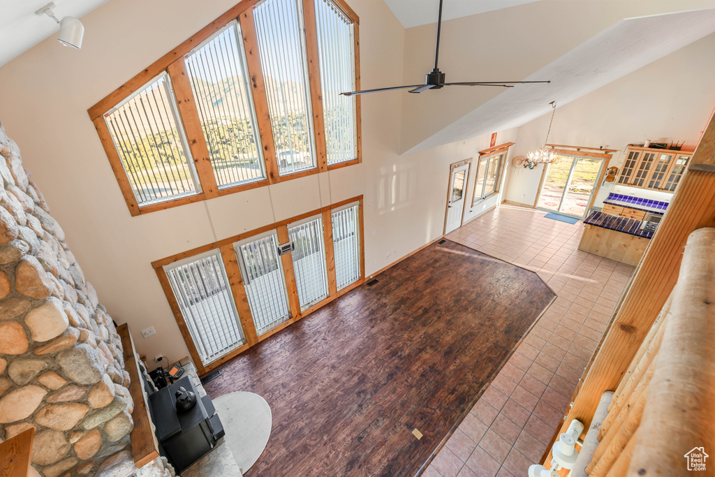 Tiled living room featuring french doors, ceiling fan with notable chandelier, and high vaulted ceiling