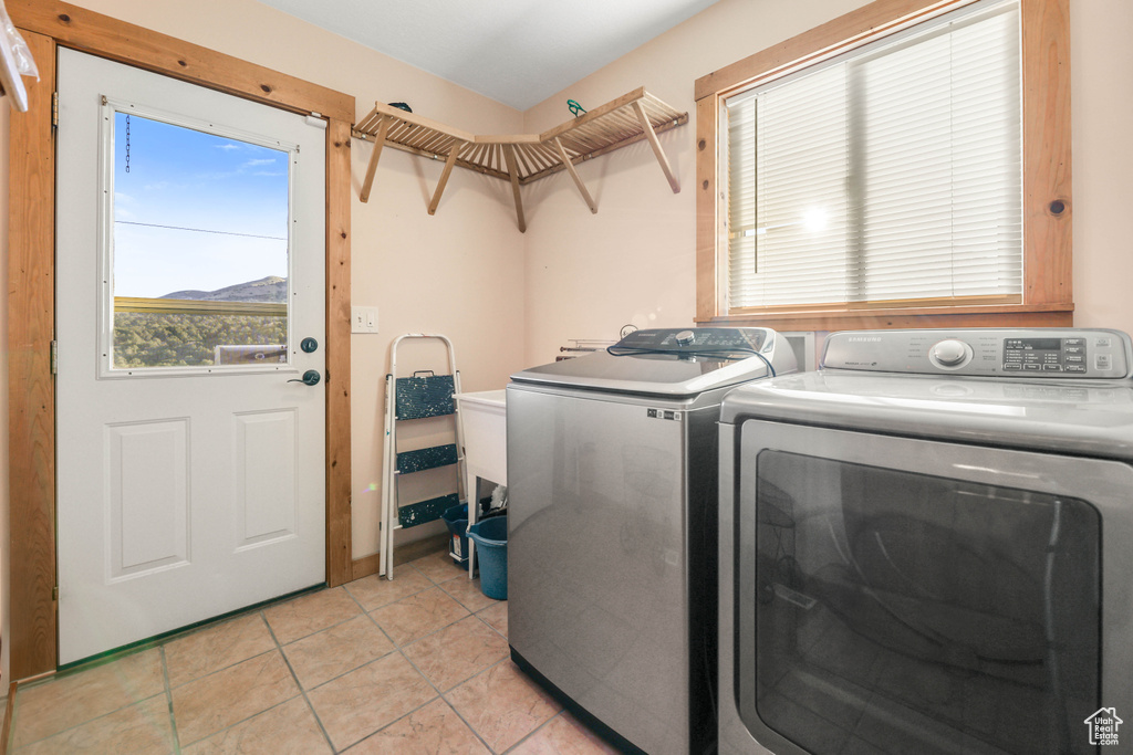 Washroom with laundry area, light tile patterned floors, and separate washer and dryer