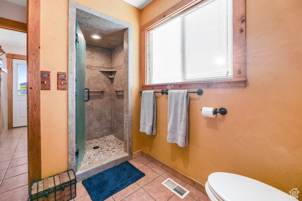 Bathroom with tile patterned flooring, toilet, baseboards, visible vents, and a stall shower