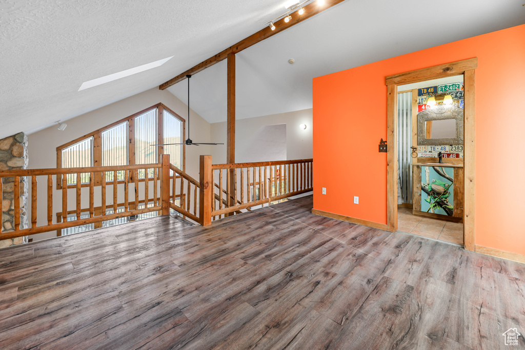 Additional living space with baseboards, wood finished floors, and vaulted ceiling with skylight