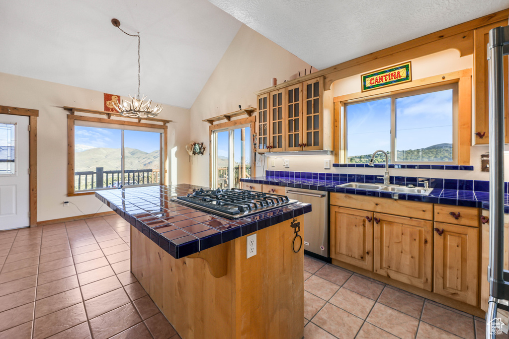 Kitchen featuring a sink, a notable chandelier, tile counters, stainless steel appliances, and light tile patterned flooring