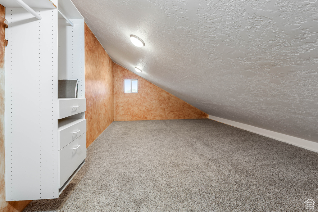 Bonus room featuring carpet floors, a textured ceiling, and lofted ceiling