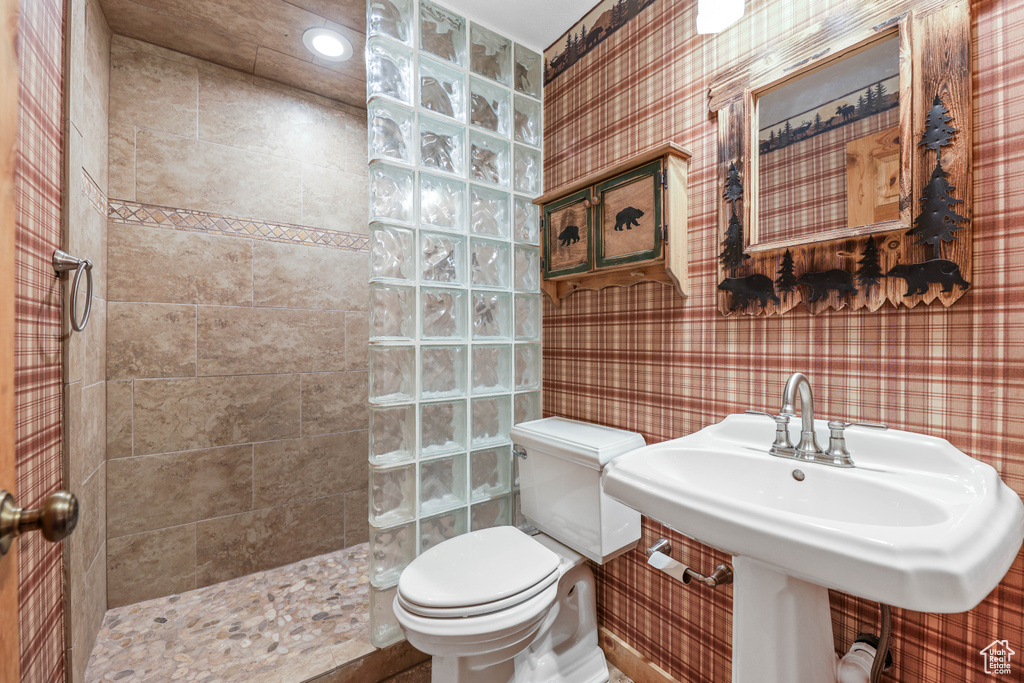 Full bath featuring a walk in shower, a sink, toilet, recessed lighting, and wallpapered walls