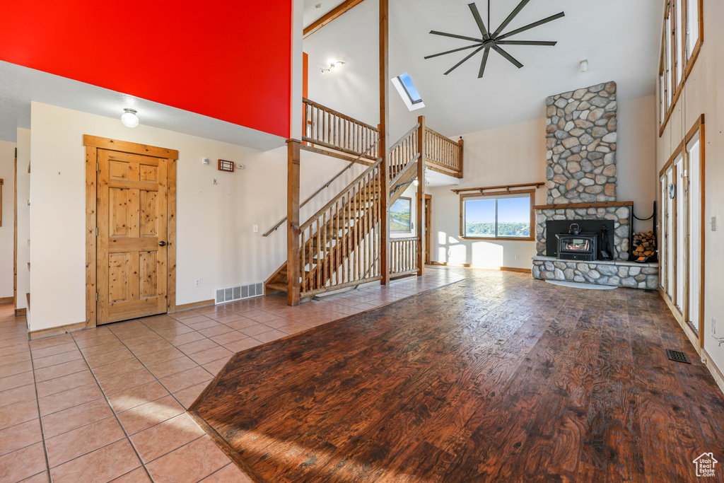 Unfurnished living room featuring high vaulted ceiling, a fireplace, stairs, and visible vents