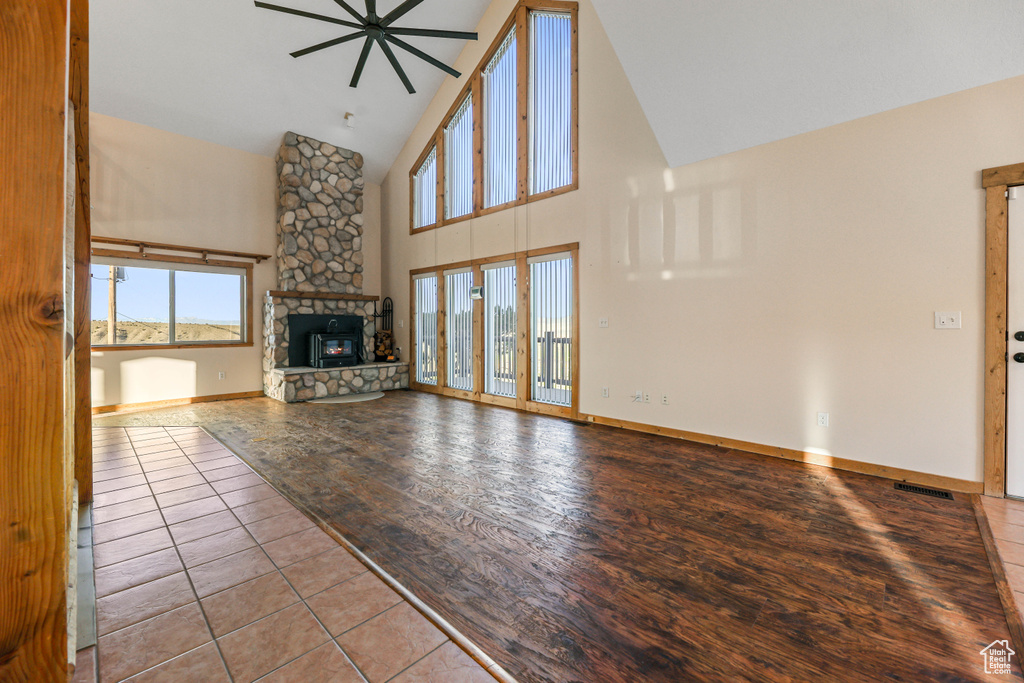 Unfurnished living room with a healthy amount of sunlight, high vaulted ceiling, ceiling fan, and a fireplace