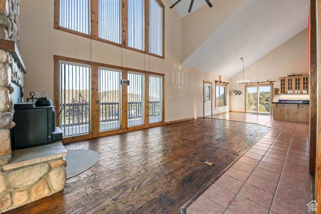 Living area featuring baseboards, ceiling fan with notable chandelier, wood finished floors, and high vaulted ceiling