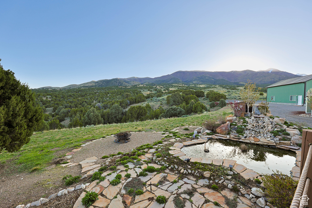 Exterior space with a mountain view, an outdoor fire pit, and a small pond