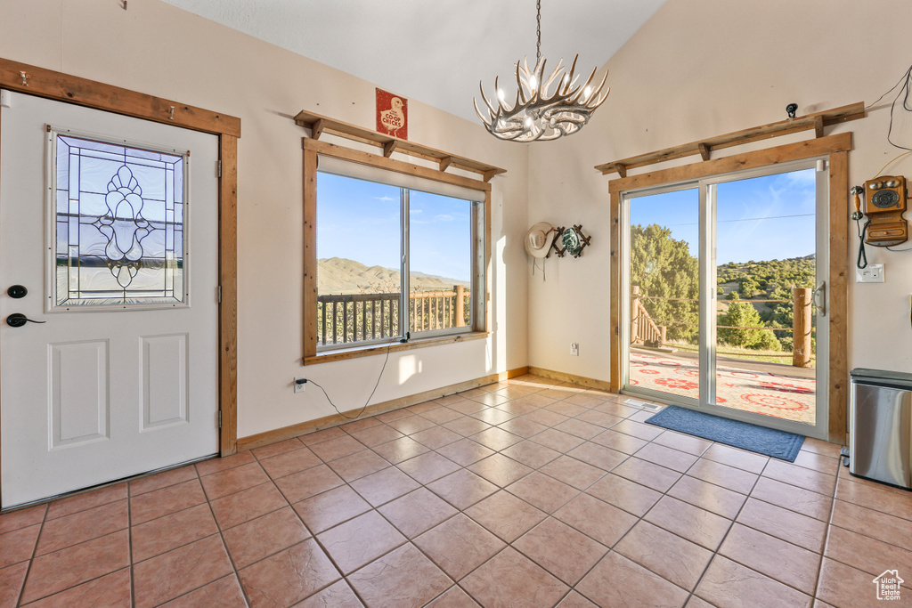 Tiled entrance foyer featuring plenty of natural light, baseboards, lofted ceiling, and a chandelier