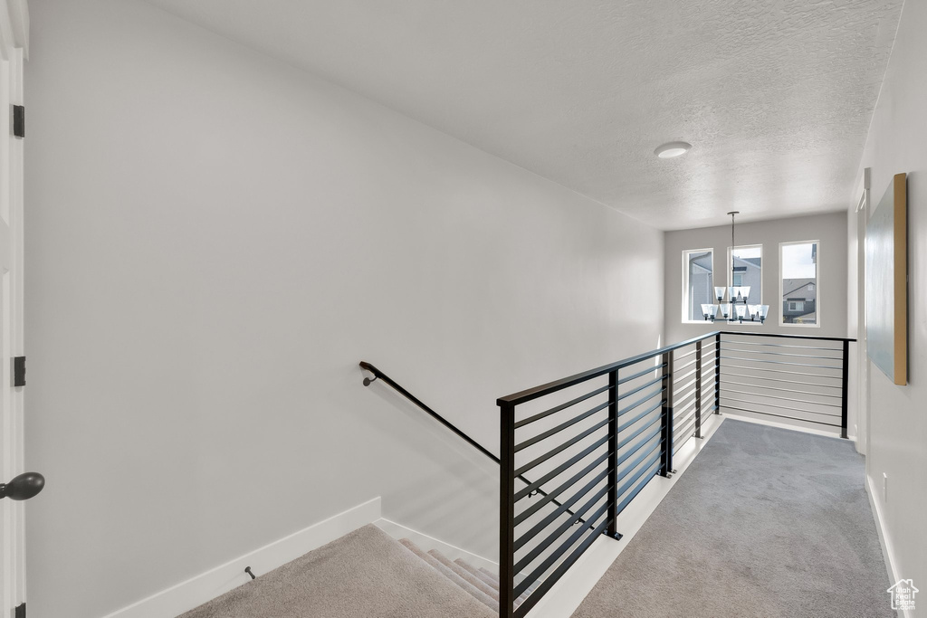Stairway with a textured ceiling, baseboards, a chandelier, and carpet