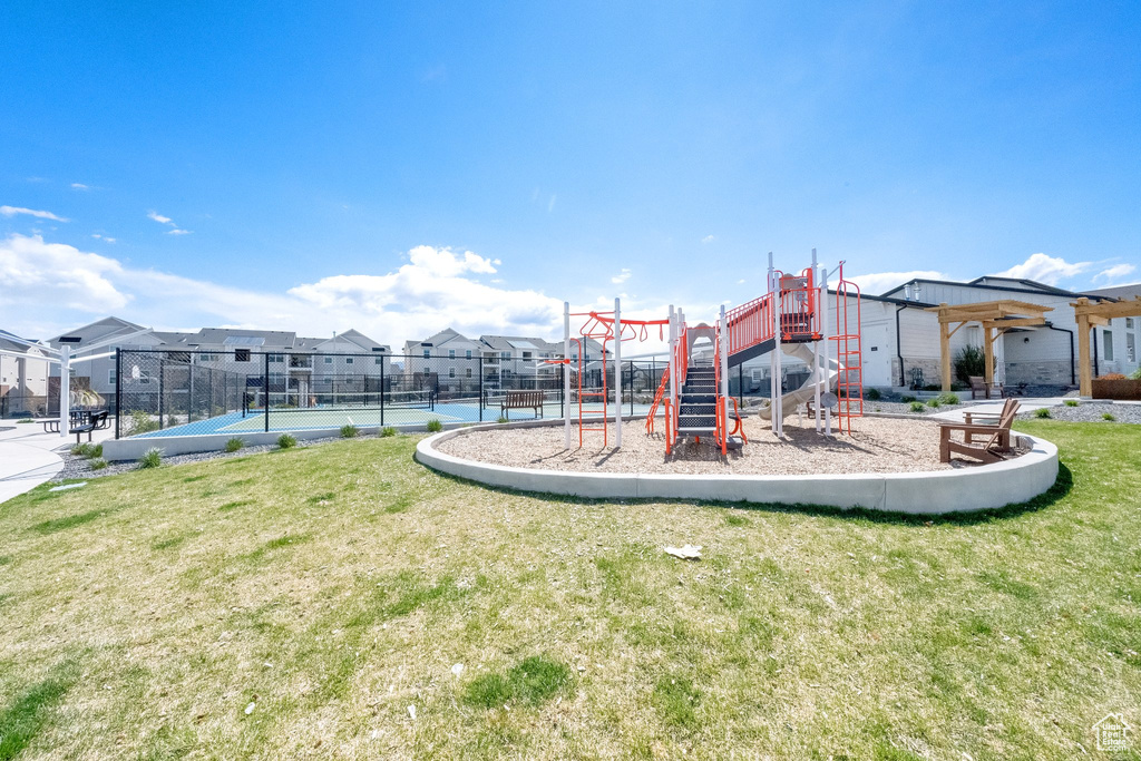Community play area featuring fence, a yard, a residential view, and a tennis court