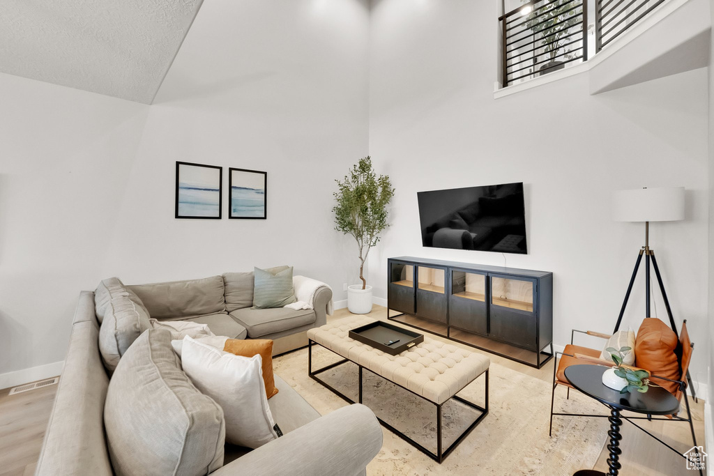 Living room with baseboards, a high ceiling, wood finished floors, and visible vents