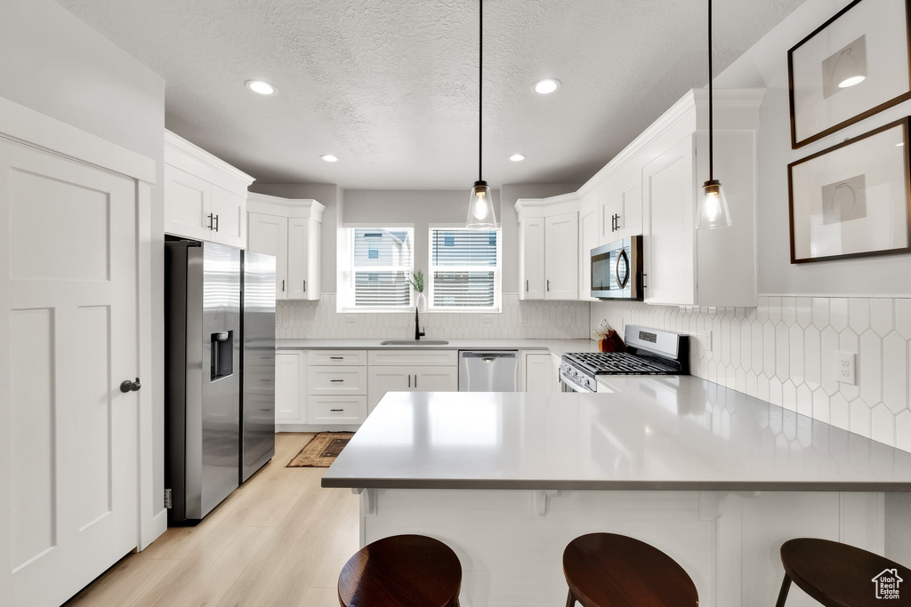 Kitchen with decorative backsplash, appliances with stainless steel finishes, a sink, a peninsula, and recessed lighting