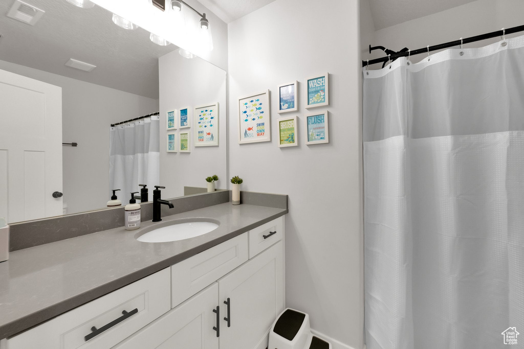 Full bath with visible vents, curtained shower, and vanity