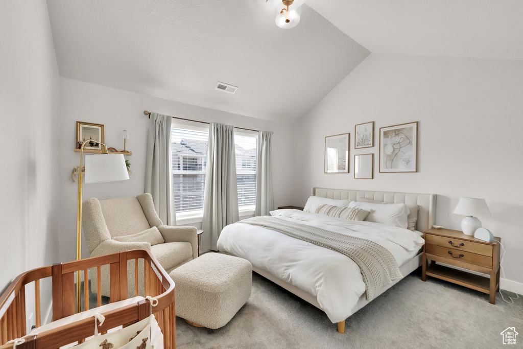 Bedroom with light carpet, lofted ceiling, and visible vents