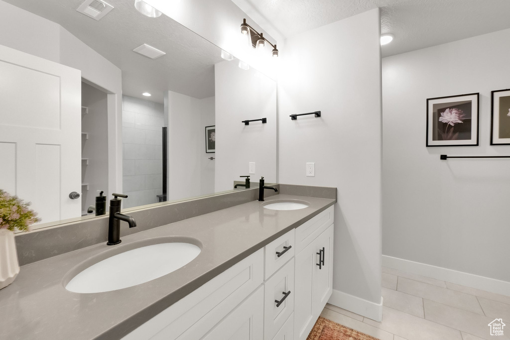 Bathroom featuring a sink, baseboards, double vanity, and visible vents