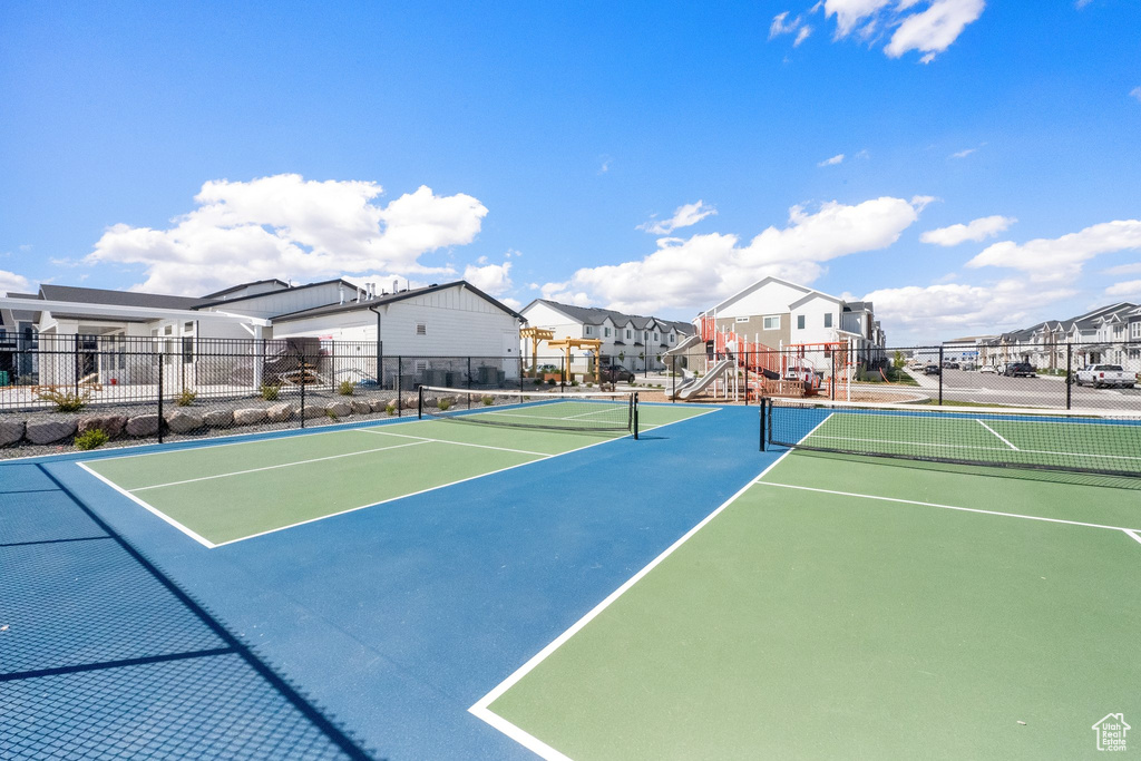 View of tennis court with fence and a residential view