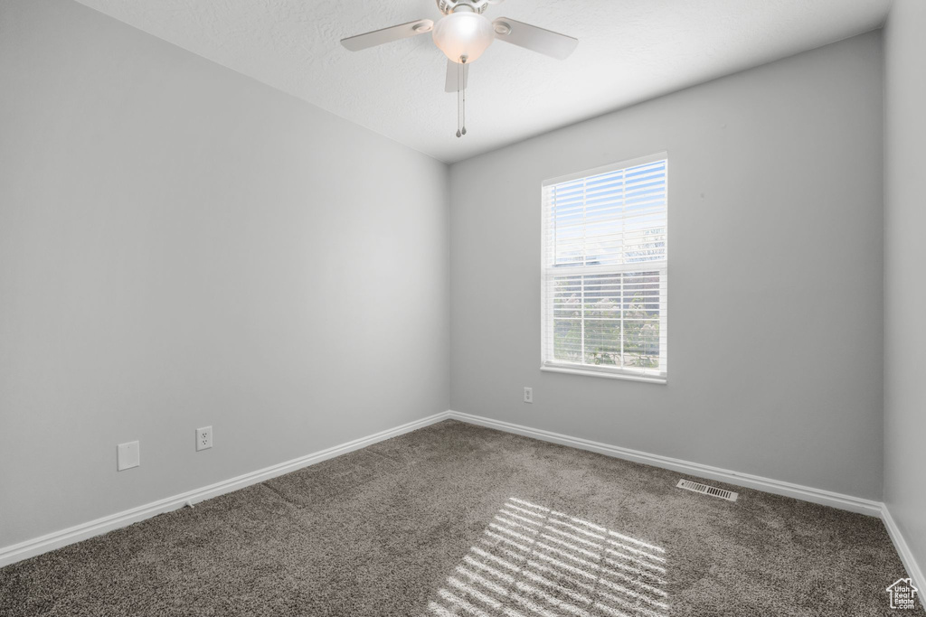 Carpeted empty room featuring baseboards, visible vents, and ceiling fan