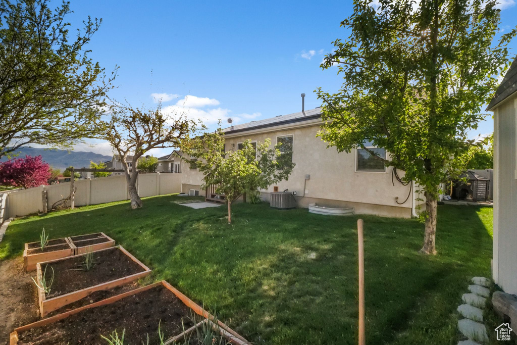 View of yard featuring fence, cooling unit, and a garden
