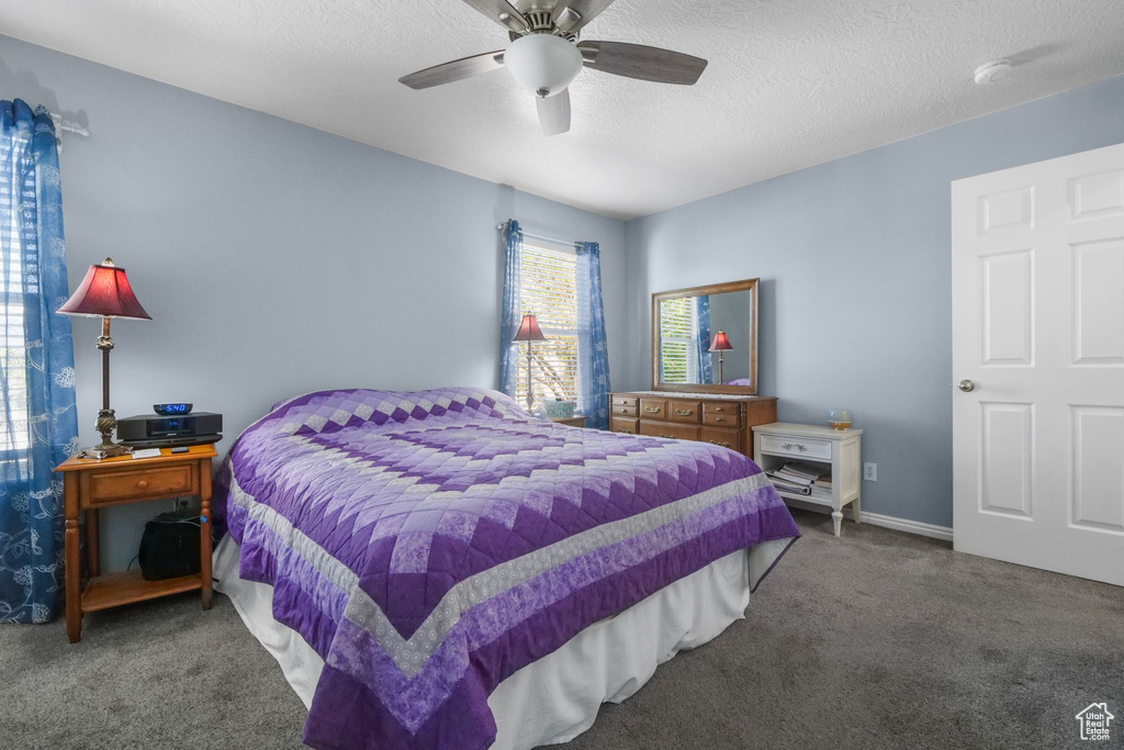 Carpeted bedroom with a ceiling fan and a textured ceiling