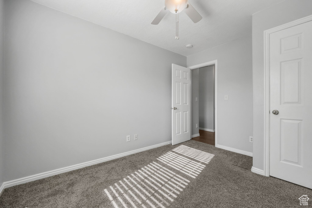 Unfurnished bedroom featuring carpet floors, a ceiling fan, and baseboards