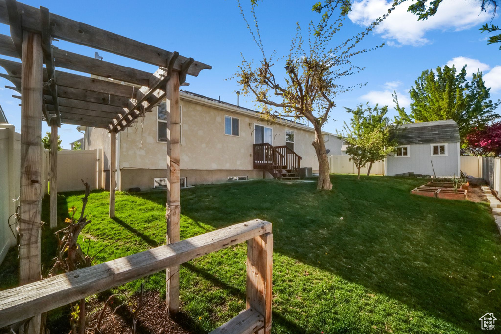 View of yard featuring an outdoor structure, a pergola, and a fenced backyard
