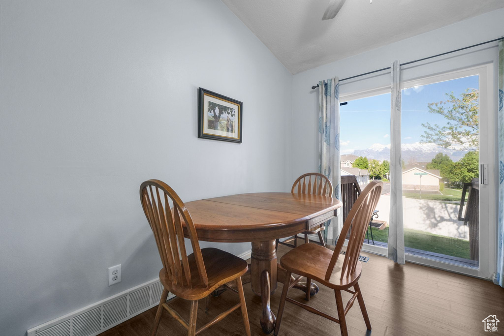 Dining space with a ceiling fan, visible vents, wood finished floors, and vaulted ceiling