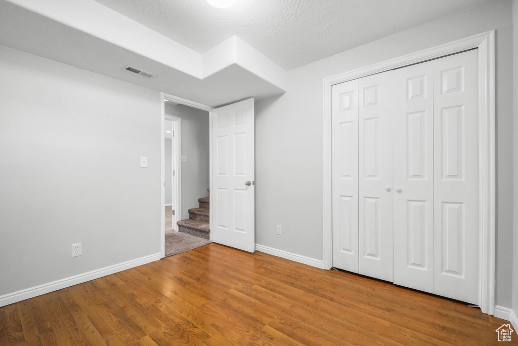 Unfurnished bedroom featuring visible vents, baseboards, wood finished floors, and a closet