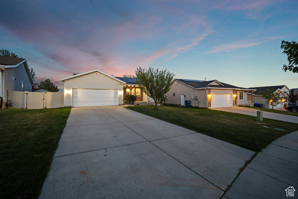 Ranch-style home featuring a front yard, a gate, roof mounted solar panels, an attached garage, and driveway