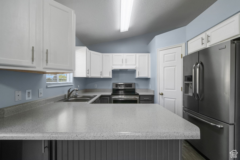 Kitchen featuring a sink, stainless steel appliances, white cabinetry, and lofted ceiling