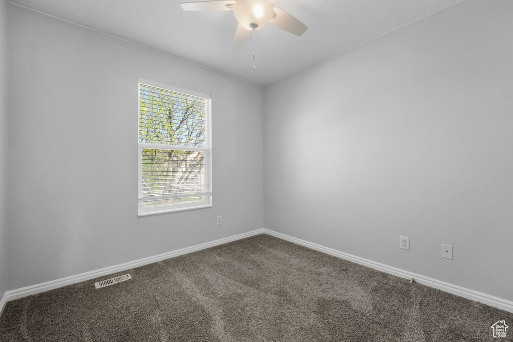 Spare room with visible vents, carpet, ceiling fan, and baseboards