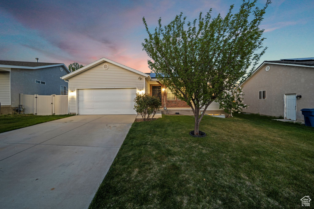 View of front of home with a garage, a gate, roof mounted solar panels, concrete driveway, and a lawn
