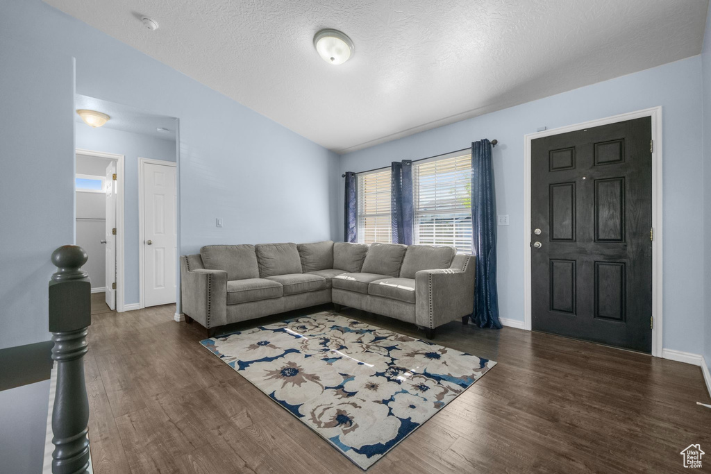 Living area with a textured ceiling, baseboards, and wood finished floors